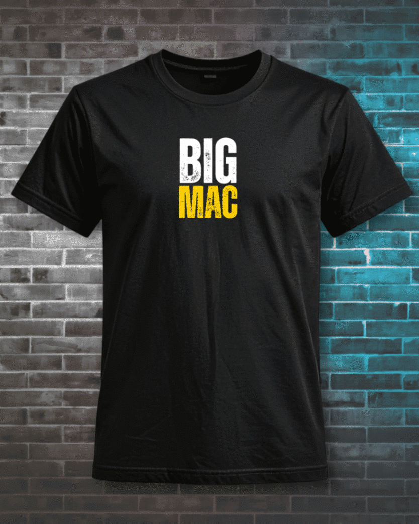 Black T-shirt printed with BIG MAC lettering in white and yellow, photographed against a blue-lit brick wall